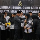 Bupati Aceh Besar H. Muharram Idris memakai slempang pada Bunda Guru Aceh Besar Hj. Rita Maysari di Orion Hall, Kecamatan Darul Imarah, Jumat (6/2/2026) malam. FOTO/MC ACEH BESAR