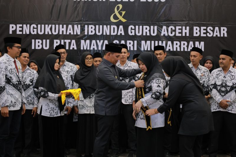 Bupati Aceh Besar H. Muharram Idris memakai slempang pada Bunda Guru Aceh Besar Hj. Rita Maysari di Orion Hall, Kecamatan Darul Imarah, Jumat (6/2/2026) malam. FOTO/MC ACEH BESAR